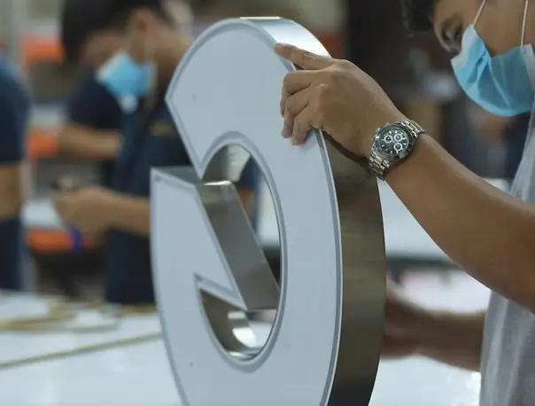 Workshop staff assembling a metal channel letter