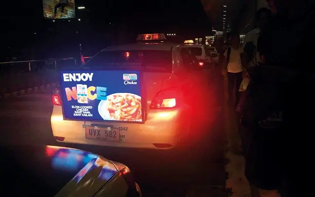 Illuminated taxi advertisement at night