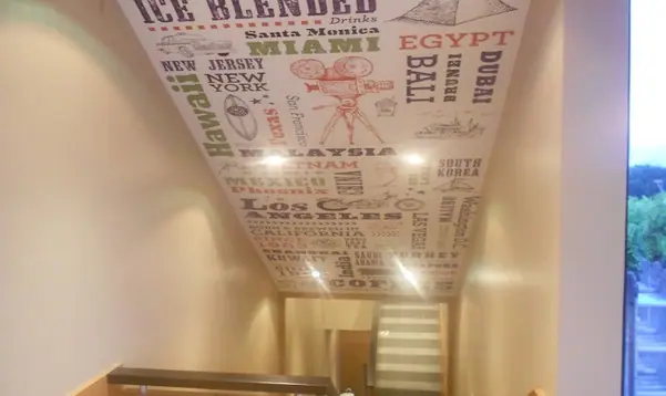 Typographic travel-themed wallpaper across a wall and ceiling
